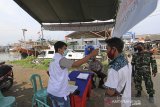 Petugas memeriksa suhu tubuh warga di pos pemeriksaan (check point) pelabuhan perikanan, Karangsong, Indramayu, Jawa Barat, Rabu (6/5/2020). Pemeriksaan tersebut sebagai upaya penyekatan dan mencegah penyebaran virus COVID-19 terhadap nelayan yang pulang melaut. ANTARA JABAR/Dedhez Anggara/agr