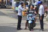 Petugas megur warga yang tidak mengenakan masker saat melintas di pos pemeriksaan (check point) pelabuhan perikanan, Karangsong, Indramayu, Jawa Barat, Rabu (6/5/2020). Pemeriksaan tersebut sebagai upaya penyekatan dan mencegah penyebaran virus COVID-19 terhadap nelayan yang pulang melaut. ANTARA JABAR/Dedhez Anggara/agr