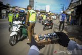 Petugas menghitung jumlah kendaraan yang melintas di titik pemeriksaan Pembatasan Sosial Berskala Besar (PSBB) di Jatinangor, perbatasan Kabupaten Bandung dan Kabupaten Sumedang, Jawa Barat, Rabu (6/5/2020). Pemerintah Kabupaten Sumedang memperpanjang masa PSBB di 26 Kecamatan selama dua minggu kedepan serta menerapkan sanksi berupa pidana yang tercatat di SKCK. ANTARA JABAR/Raisan Al Farisi/agr