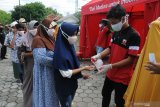 Petugas menyemprotkan cairan hand sanitizer kepada warga saat pembagian paket sembako  di Pamekasan, Jawa Timur, Sabtu (9/5/2020). MU menyalurkan 4.300 paket sembako kepada warga terdampak COVID-19. Antara Jatim/Saiful Bahri/zk