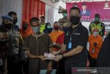 Menteri Sosial Juliari P Batubara (kedua kanan) memberikan Bantuan Sosial Tunai (BST) kepada Keluarga Penerima Manfaat (KPM) saat melakukan kunjungan kerja di Cimahi, Jawa Barat, Minggu (10/5/2020). Dalam kunjungan kerja tersebut, Menteri Sosial memantau penyaluran bantuan sosial tunai di Cimahi dan Kabupaten Bandung Barat yang menggunakan skema pemanggilan KPM dan pengumpulan komunitas. ANTARA JABAR/Raisan Al Farisi/agr