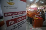 Petugas memberikan Bantuan Sosial Tunai (BST) pada Keluarga Penerima Manfaat (KPM) di Kantor Pos Cimahi, Jawa Barat, Minggu (10/5/2020). Pemerintah melalui Kementerian Sosial menyalurkan dana bantuan sosial tunai senilai Rp 600.000 kepada 13.491 Keluarga Penerima Manfaat di Kota Cimahi yang terdampak wabah COVID-19. ANTARA JABAR/Raisan Al Farisi/agr