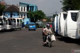 Pengendara motor melintas di depan puluhan bus antar kota yang terparkir dan tidak beroperasi di terminal Landungsari, Malang, Jawa Timur, Senin (11/5/2020). Pengusaha armada bus setempat memilih untuk tidak beroperasi dan meliburkan seluruh armada yg dimiliki meski Kementerian Perhubungan memberi kelonggaran aktivitas transportasi di tengah pandemi COVID-19. Antara Jatim/Ari Bowo Sucipto/zk.