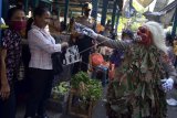 Petugas kepolisian yang mengenakan kostum menyeramkan 'Celuluk' membagikan masker saat sosialisasi langkah-langkah pencegahan COVID-19 di Pasar Tradisional Sempidi, Badung, Bali, Selasa (12/5/2020). Kegiatan yang dilakukan petugas kepolisian Polres Badung di sejumlah pasar tradisional dan ruas jalan tersebut dilakukan untuk mengimbau masyarakat terus melakukan berbagai upaya pencegahan penyebaran COVID-19 seperti mengenakan masker, rutin mencuci tangan, menjaga jarak serta tidak melakukan perjalanan mudik. ANTARA FOTO/Fikri Yusuf/nym.