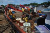 Buruh melakukan aktivitas bongkar muat bahan bakar jenis solar dan gas elpiji di dermaga Sungai Krueng Aceh, Desa Lampulo, Banda Aceh, Aceh, Kamis (14/5/2020). Pengapalan minyak solar menggunakan drum dan tabung gas elpiji itu berjalan normal dan tidak terdampak pandemi COVID-19 untuk kebutuhan warga dan nelayan di wilayar terluar Pulau Aceh.Antara Aceh/Ampelsa.