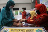 Petugas menyerahkan Bantuan Langsung Tunai (BLT) dana desa kepada warga di Balai desa Janti, Waru, Sidoarjo, Jawa Timur, Kamis (14/5/2020). Bantuan langsung tunai (BLT) dari pemerintah melalui Kementerian Desa, Pembangunan Daerah Tertinggal, dan Transmigrasi sebesar Rp600 ribu perbulan selama tiga bulan diberikan kepada warga miskin, orang sakit kronis bertahun-tahun, dan orang kehilangan pekerjaan karena pandemi Corona Virus Disease (COVID-19). Antara Jatim/Umarul Faruq/zk