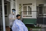 Seorang pegiat jasa pangkas rambut panggilan bersiap untuk memangkas rambut pelanggannya di Arcamanik, Bandung, Jawa Barat, Sabtu (16/5/2020). Setelah kehilangan pekerjaan akibat wabah COVID-19, pegiat pangkas rambut tersebut berinisiatif untuk membuka jasa panggilan bagi warga yang ingin bercukur agar tetap mendapatkan penghasilan di tengah pandemi. ANTARA JABAR/Raisan Al Farisi/agr