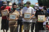 Warga menerima paket Ramadhan di kampung nelayan Kenjeran Surabaya, Jawa Timur, Sabtu (16/5/2020). Pambagian paket Ramadhan oleh Yayasan Manarul Ilmi (YMI) ITS bersama Aksi Cepat Tanggap (ACT) kepada para nelayan dan pengemudi taksi itu untuk meringankan beban ekonomi mereka di tengah wabah COVID-19. Antara Jatim/Didik/Zk