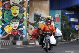 Pengendara motor melintas di depan mural topeng malangan saat pemberlakuan Pembatasan Sosial Berskala Besar (PSBB) hari pertama di Jalan Raya Ahmad Yani, Malang, Jawa Timur, Minggu (17/5/2020). Pemerintah resmi memberlakukan Pembatasan Sosial Berskala Besar (PSBB) untuk kawasan Malang Raya yakni Kota Malang, Kabupaten Malang dan Kota Batu mulai tanggal 17 Mei 2020 sebagai upaya pencegahan penyebaran COVID-19. Antara Jatim/Ari Bowo Sucipto/zk