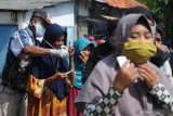 Petugas memakaikan masker kepada penerima sembako di Kantor Madura United FC (MU) di Pamekasan, Jawa Timur, Selasa (19/5/2020). Hingga memasuki akhir Ramadhan 1441 H. Madura United FC (MU) telah menyalurkan lebih dari 10.000 paket sembako tahap ke tiga, yang diberikan kepada masyarakat terdapat COVID-19. Antara Jatim/Saiful Bahri/zk