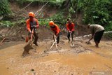 Petugas Badan Penanggulangan Bencana Daerah (BPBD) Banyuwangi membersihkan lumpur yang menutupi jalan akibat longsor di Desa Kluncing, Licin, Banyuwangi, Jawa Timur, Senin (18/5/2020). Tanah longsor di kaki Gunung Ijen yang menyebabkan akses jalan penghubung Desa Pakel dengan Desa Kluncing  tertutup itu, terjadi akibat intensitas hujan deras yang mengguyur kawasan tersebut sejak pagi hingga sore hari. Antara Jatim/Budi Candra Setya/zk