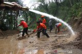 Petugas Badan Penanggulangan Bencana Daerah (BPBD) Banyuwangi membersihkan lumpur yang menutupi jalan akibat longsor di Desa Kluncing, Licin, Banyuwangi, Jawa Timur, Senin (18/5/2020). Tanah longsor di kaki Gunung Ijen yang menyebabkan akses jalan penghubung Desa Pakel dengan Desa Kluncing  tertutup itu, terjadi akibat intensitas hujan deras yang mengguyur kawasan tersebut sejak pagi hingga sore hari. Antara Jatim/Budi Candra Setya/zk