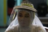 Mempelai wanita Ika Wahyuning Sejati mengikuti rangkaian prosesi akad nikah dengan calon suaminya Yoga Priantha di Kantor Urusan Agama (KUA) Tandes, Surabaya, Jawa Timur, Kamis (21/5/2020). Pemerintah melalui Kementerian Agama mengizinkan diselenggarakannya prosesi akad nikah di tengah pandemi COVID-19 dengan syarat mematuhi protokol kesehatan di antaranya dihadiri tidak lebih dari 10 orang, menggunakan masker serta menjaga jarak fisik guna mencegah penyebaran virus corona. Antara Jatim/Moch Asim/zk.