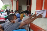 Warga melihat jadwal saat mengantre pembagian  Bantauan Sosial Tunai (BST) di Kantor Pos Banyuwangi, Jawa Timur, kamis (21/5/2020). Pembagian BST senilai Rp600 ribu kepada Keluarga Penerima Manfaat itu, untuk membantu meringankan beban ekonomi masyarakat saat pendemi COVID-19. Antara Jatim/Budi Candra Setya/zk