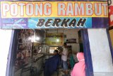 Tukang potong memangkas rambut pelanggannya di kawasan Kampung Cukur Kelurahan Kemasan, Kota Kediri, Jawa Timur, Sabtu (23/5/2020). Semenjak pandemi COVID-19 belasan tukang cukur di kawasan tersebut sepi pelanggan sehingga rata-rata penghasilan mereka menurun hingga 40 persen dan tidak ada peningkatan meskipun menjelang lebaran. Antara Jatim/Prasetia Fauzani/zk