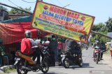 Warga melewati portal dengan penjagaan petugas linmas di Desa Tugurejo, Kediri, Jawa Timur, Sabtu (23/5/2020). Sejumlah desa di Kediri menutup akses masuk wilayahnya untuk mengantisipasi warga luar desa berkunjung saat lebaran guna menangkal penyebaran COVID-19. Antara Jatim/Prasetia Fauzani/zk