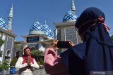 Warga membuat rekaman video ucapan selamat Hari Raya Idul Fitri menggunakan kamera telepon pintar di halaman Masjid Agung Baitul Hakim Kota Madiun, Jawa Timur, Sabtu (23/5/2020). Video tersebut selanjutnya akan dikirim kepada kerabatnya melalui media sosial karena adanya imbauan pemerintah untuk tidak melakukan silaturahmi secara langsun saat Idul Fitri yang jatuh pada Minggu (24/5) dan dianjurkan bersilaturahmi menggunakan fasilitas telepon maupun media sosial guna mencegah penyebaran COVID-19. Antara Jatim/Siswowidodo/zk.