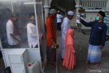 Takmir masjid mengukur suhu tubuh para jemaah sebelum mengikuti Shalat Id saat Hari Raya Idul Fitri 1 Syawal 1441 H di Masjid Agung Jamik, Malang, Jawa Timur, Minggu (24/5/2020). Shalat Id di tengah penerapan Pembatasan Sosial Berskala besar (PSBB) Malang Raya tersebut pelaksanaanya dipercepat untuk meminimalisir penyebaran COVID-19. Antara Jatim/Ari Bowo Sucipto/zk.