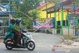 Pengendara motor melintas di dekat jalan komplek perumahan yang ditutup di Kelurahan Banua Anyar, Banjarmasin, Kalimantan Selatan, Senin (25/5/2020). Warga Kelurahan Banua Anyar di lima RT melakukan isolasi mandiri untuk mencegah keluar masuknya orang dalam upaya memutus mata rantai penyebaran COVID-19. Foto Antaranews Kalsel/Bayu Pratama S.