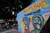 Warga melintas di depan mural bertema Hidup Sehat Lawan COVID-19 di Serengan, Solo, Jawa Tengah, (27/5/2020). Pemerintah Kota Solo kembali memperpanjang status Kejadian Luar Biasa (KLB) hingga 7 Juni 2020 mendatang, menyusul temuan empat pasien baru positif COVID-19. ANTARA FOTO/Maulana Surya/nym.