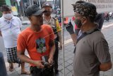 Petugas desa adat menegur warga yang tidak menggunakan masker saat penerapan Pembatasan Kegiatan Masyarakat (PKM) di wilayah Desa Adat Panjer, Denpasar, Bali, Kamis (28/5/2020). Sebanyak lima kelurahan / desa adat di Denpasar mulai menerapkan PKM di wilayahnya masing-masing pada 28 Mei hingga 28 Juni 2020 untuk memutus rantai penyebaran COVID-19. ANTARA FOTO/Nyoman Hendra Wibowo/nym.