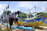 Nelayan memperbaiki perahunya di kawasan Pantai Kedonganan, Badung, Bali, Jumat (29/5/2020). Nelayan tradisional di kawasan tersebut memilih untuk tidak melaut akibat gelombang tinggi yang terjadi sejak tiga hari terakhir di perairan selatan Pulau Bali yang dapat membahayakan keselamatan nelayan. ANTARA FOTO/Fikri Yusuf/nym.