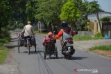 Seorang warga membantu mendorong sepeda roda tiga penyandang disabilitas yang melintas Jalan Raya Primono, Kabupaten Jombang, Jawa Timur, Sabtu (30/5/2020). Penyandang disabilitas merupakan salah satu kelompok masyarakat yang paling terdampak selama pandemi virus Corona (COVID-19). Bahkan menurut Badan Koordinasi Kegiatan Kesejahteraan Sosial (BK3S) Provinsi Jawa Timur, banyak penyandang disabilitas yang kehilangan pekerjaannya sebagai pemijat, pemotong rambut, tukang sablon. Antara Jatim/Syaiful Arif/zk