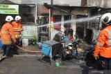 Petugas Dinas Pemadam Kebakaran Kota Surabaya melakukan pembasahan kios bensin yang terbakar di Jalan Lebak Jaya Utara, Surabaya, Jawa Timur, Selasa (2/6/2020). Sebanyak tujuh kendaraan pemadam kebakaran dikerahkan untuk memadamkan kebakaran yang mengakibatkan dua warga, ayah dan anaknya, mengalami luka bakar. Antara Jatim/Didik/Zk