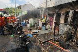 Petugas Dinas Pemadam Kebakaran Kota Surabaya melakukan pembasahan kios bensin yang terbakar di Jalan Lebak Jaya Utara, Surabaya, Jawa Timur, Selasa (2/6/2020). Sebanyak tujuh kendaraan pemadam kebakaran dikerahkan untuk memadamkan kebakaran yang mengakibatkan dua warga, ayah dan anaknya, mengalami luka bakar. Antara Jatim/Didik/Zk