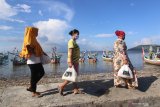 Warga membawa sembako bantuan Polairud Banyuwangi di pesisir Muncar, Banyuwangi, Jawa Timur, Selasa (2/6/2020). Bantuan sembako untuk  masyarakat pesisir terdampak cuaca buruk dimasa Pandemi  COVID-19 yang belum mendapatkan bantuan dari pemerintah itu, sebagai upaya dalam meringankan beban ekonomi masyarakat nelayan. Antara Jatim/Budi Candra Setya/zk