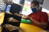 Karyawan membersihkan koleksi gigi hiu purba atau Megalodon di Perpustakaan SMK 4, Malang, Jawa Timur, Rabu (3/6/2020). Perawatan koleksi benda kuno tersebut dilakukan menjelang dibukanya kembali perpustakaan sekolah dengan penerapan normal baru. Antara Jatim/Ari Bowo Sucipto/zk