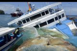 Petugas melakukan penanggulangan tumpahan minyak di sekitar area kandasnya KMP Dharma Rucitra III di Dermaga 2, Pelabuhan Padangbai, Karangasem, Bali, Sabtu (13/6/2020). Kapal yang berada dalam posisi miring karena diduga mengalami kebocoran lambung kapal tersebut, masih belum dapat dievakuasi karena menunggu teknisi dari Surabaya yang akan mengevakuasi dengan menggunakan alat untuk mengapungkan kapal. ANTARA FOTO/Fikri Yusuf/nym