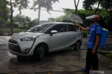 Petugas menyemprotkan cairan disinfektan pada mobil wali murid SD Islam Al Azhar (SDIA) 11 Surabaya saat mengikuti prosesi wisuda akhir tahun secara 