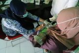 Petugas melakukan pengecekan buku kesehatan ibu dan anak sebelum memberikan imunisasi kepada bayi di kantor Kelurahan Pesantren, Kota Kediri, Jawa Timur, Rabu (17/6/2020). Memasuki era transisi normal baru pemberian imunisasi untuk balita di wilayah tersebut diberlakukan penjatwalan berdasarkan domisili per kelurahan guna menghindari kerumunan pemicu penyebaran COVID-19. Antara Jatim/Prasetia Fauzani/zk.