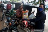 Sekretaris Pewarta Foto Indonesia, Banda Aceh, Eko Deni Saputra (kanan) menyerakan sembako kepada pengemudi becak mesin di Banda Aceh, Rabu (17/6/2020). PT XL Axiata Area Banda Aceh menggandeng Pewarta Foto Indonesia (PFI) Banda Aceh dalam bhakti sosial penyaluran sembako untuk pengemudi becak dan masyarakat kurang mampu yang terdampak pandemi COVID-19. Antara Aceh/Ampelsa.