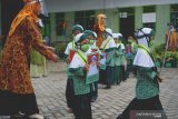 Guru memandu siswa berjalan keluar secara bergilir sembari memegang poster bergambar foto diri mereka di akhir sesi pournawiyata di TK Al Khodijah, Tiudan, Tulungagung, Jawa Timur, Sabtu (20/6/2020). Memasuki era kenormalan baru sekolah ini menerapkan protokol kesehatan ketat saat melaksanakan seremoni wisuda 60 siswa TK dan KB (kelompok belajar/pendidikan usia dini) setempat dengan tujuan untuk mencegah penularan virus COVID-19. Antara Jatim/Destyan Sujarwoko/zk