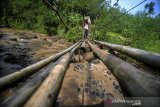 Seorang buruh tani menyeberangi jembatan gantung yang rapuh di Desa Kertamukti, Kabupaten Bandung Barat, Jawa Barat, Rabu (24/6/2020). Menurut keterangan warga setempat, jembatan yang telah ada pada 1980-an dan menjadi penghubung antara Desa Kertamukti dan Desa Cipatat tersebut saat ini kondisinya rusak parah dan warga berharap adanya perbaikan dari pemerintah setempat. ANTARA JABAR/Raisan Al Farisi/agr