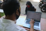 Seorang guru membantu wali murid mengisikan data saat Penerimaan Peserta Didik Baru (PPDB) daring jalur zonasi tingkat SMP di SD Negeri Pesantren 2, Kota Kediri, Jawa Timur, Rabu (25/6/2020). Sejumlah SD di daerah itu membuka layanan bantuan pendaftaran PPDB daring ke jenjang SMP kepada alumninya agar tidak terjadi kesalahan dalam mendaftar karena kekurangtahuan wali murid. Antara Jatim/Prasetia Fauzani/zk.