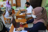 Dua orang guru membantu wali murid mengisikan data saat Penerimaan Peserta Didik Baru (PPDB) daring jalur zonasi tingkat SMP di SD Negeri Pesantren 2, Kota Kediri, Jawa Timur, Rabu (25/6/2020). Sejumlah SD di daerah itu membuka layanan bantuan pendaftaran PPDB daring ke jenjang SMP kepada alumninya agar tidak terjadi kesalahan dalam mendaftar karena kekurangtahuan wali murid. Antara Jatim/Prasetia Fauzani/zk.