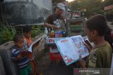 Sejumlah bocah membaca buku yang dibawa penjual pentol Lutfan Efendi di Desa Ngudirejo, Kecamatan Diwek, Kabupaten Jombang, Jawa Timur, Sabtu (27/6/2020). Lutfan Efendi membawa buku bacaan mulai dari pengetahuan, buku cerita dan buku bacaan lainnya guna menumbuhkan minat baca masyarakat terutama anak-anak sembari berjualan. Antara Jatim/Syaiful Arif/zk.