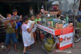 Sejumlah bocah membaca buku yang dibawa penjual pentol Lutfan Efendi di Desa Ngudirejo, Kecamatan Diwek, Kabupaten Jombang, Jawa Timur, Sabtu (27/6/2020). Lutfan Efendi membawa buku bacaan mulai dari pengetahuan, buku cerita dan buku bacaan lainnya guna menumbuhkan minat baca masyarakat terutama anak-anak sembari berjualan. Antara Jatim/Syaiful Arif/zk.