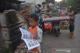 Sejumlah bocah membaca buku yang dibawa penjual pentol Lutfan Efendi di Desa Ngudirejo, Kecamatan Diwek, Kabupaten Jombang, Jawa Timur, Sabtu (27/6/2020). Lutfan Efendi membawa buku bacaan mulai dari pengetahuan, buku cerita dan buku bacaan lainnya guna menumbuhkan minat baca masyarakat terutama anak-anak sembari berjualan. Antara Jatim/Syaiful Arif/zk.