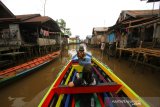 Wisatawan menikmati pemandangan rumah yang berada di bantaran anak sungai Martapura saat wisata susur sungai di Banjarmasin, Kalimantan Selatan, Sabtu (27/6/2020). Pemprov Kalimantan Selatan terus berupaya meningkatkan kunjungan pariwisata, salah satunya wisata susur sungai di Banjarmasin yang menawarkan suasana alam serta aktivitas warga di bantaran sungai untuk menggaet para wisatawan baik dari dalam negeri maupun luar negeri. Foto Antaranews Kalsel/Bayu Pratama S