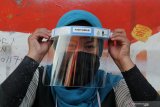 Pedagang memakai alat pelindung wajah (face shield) yang didapat dari pembagian Alat Pelindung Diri (APD) di Pasar Keputih, Surabaya, Jawa Timur, Minggu (28/6/2020). Yayasan Manarul Ilmi (YMI) ITS membagikan sekitar 500 pelindung wajah (face shield), 500 masker, 500 sarung tangan karet dan selebaran 'Sehat dan Berani Bersih Lawan COVID-19 Di Pasar Rakyat' kepada pedagang-pedagang setempat guna mengedukasi pentingnya menerapkan protokol pencegahan penularan COVID-19 khususnya di lingkungan pasar tradisional. Antara Jatim/Didik/Zk