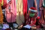 Pedagang dengan memakai alat pelindung wajah (face shield) membaca  selebaran 'Sehat dan Berani Bersih Lawan COVID-19 Di Pasar Rakyat' yang didapat dari pembagian Alat Pelindung Diri (APD) di Pasar Keputih, Surabaya, Jawa Timur, Minggu (28/6/2020). Yayasan Manarul Ilmi (YMI) ITS membagikan sekitar 500 pelindung wajah (face shield), 500 masker, 500 sarung tangan karet dan selebaran 'Sehat dan Berani Bersih Lawan COVID-19 Di Pasar Rakyat' kepada pedagang-pedagang setempat guna mengedukasi pentingnya menerapkan protokol pencegahan penularan COVID-19 khususnya di lingkungan pasar tradisional. Antara Jatim/Didik/Zk