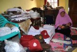 Penjahit dan pekerja saat menyelesaikan pembuatan seragam sekolah pesanan salah satu sekolah dasar (SD) di Desa Laladon, Ciomas, Kabupaten Bogor, Provinsi Jawa Barat, Minggu (28/6/2020). Menjelang tahun ajaran baru sekolah 2020/2021, pesanan seragam sekolah meningkat dari sebelumnya 250 menjadi 500 setelan seragam sekolah karena banyaknya orangtua siswa yang memesan langsung ke pihak sekolah dibandingkan membeli melalui toko seragam di saat pandemi COVID-19.  (ANTARA FOTO/Arif Firmansyah).