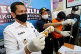 Petugas memperlihatkan tersangka berinisial HA dan barang bukti berupa ganja saat rilis peredaran narkoba melalui media sosial di kantor Badan Narkotika Nasional (BNN) Kota Kediri, Jawa Timur, Senin (29/6/2020). BNN mengamankan tersangka yang bersetatus mahasiswa tersebut bersama dengan barang bukti 23 gram ganja kering yang dipesan melalui media sosial instagram. Antara Jatim/Prasetia Fauzani/zk