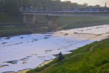 Pengendara motor melintas di samping aliran Kanal Banjir Timur (KBT) yang permukaannya dipenuhi limbah busa di Duren Sawit, Jakarta Timur, Senin (29/6/2020). Menurut petugas pintu air KBT, limbah busa biasa terjadi pada musim kemarau akibat perbedaan debit permukaan air dan pintu aliran tersebut ditutup. ANTARA FOTO/Fakhri Hermansyah/wsj.