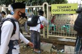 Santri mencuci tangan sebelum memasuki kawasan Pondok Pesantren (ponpes) Lirboyo, Kota Kediri, Jawa Timur, Sabtu (4/7/2020). Tahap ke dua kedatangan santri ke ponpes terbesar se-Jawa Timur tersebut sejumlah 10 ribu santri yang dilaksanakan selama 4 hari usai libur panjang akibat pandemi COVID-19. Antara Jatim/Prasetia Fauzani/zk