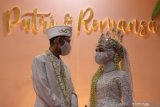 Pasangan pengantin berbincang dengan mengenakan masker dan pelindung wajah saat simulasi resepsi pernikahan di masa normal baru di Hotel Royal Singosari Cendana, Surabaya, Jawa Timur, Senin (6/7/2020). Kegiatan simulasi resepsi pernikahan tersebut bertujuan untuk mengedukasi masyarakat tentang pentingnya penerapan protokol kesehatan dalam acara pernikahan guna mencegah penyebaran dan penularan COVID-19 di masa normal baru. Antara Jatim/Moch Asim/zk.